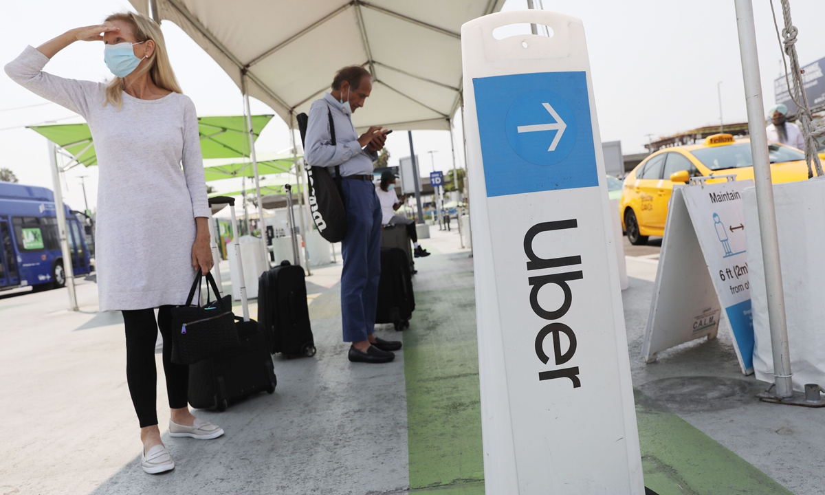 Air travelers wait in the ride share lot near a sign for Uber at Los Angeles International Airport  on August 20 in Los Angeles, California. Photo: AFP