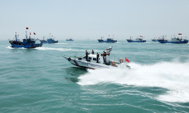 A vessel of the coast guard patrols near fishing boats at sea on Aug. 16, 2020. Chinese coast guard authority has dismantled more than 10 major criminal gangs engaged in illegal sea-related activities in the past three years. China's coast guards at all levels have launched campaigns and investigated more than 190 tip-offs, arresting more than 140 suspects, said the authority. (Photo by Zhai Shaohua/Xinhua) 