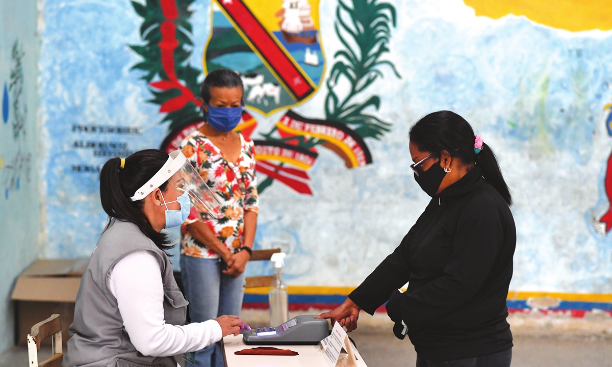 A woman wearing a mask votes at a polling station in a school in Caracas, Venezuela on Sunday for the country's legislative elections. Polls opened early in elections set to tighten Venezuelan President Nicolas Maduro's grip on power and weaken his US-backed rival Juan Guaido. Photo: AFP