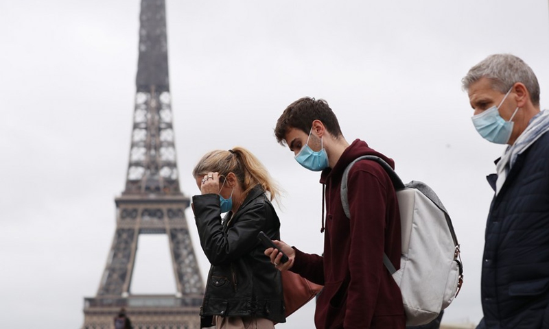 People wearing face masks walk past the Trocadero Place near the Eiffel Tower in Paris, France, Oct. 23, 2020.(Photo: Xinhua)
