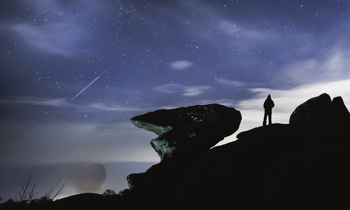 A man watches the sky during the Geminid meteor shower over Brimham Rocks, a collection of balancing rock formations in the Nidderdale Area of Outstanding Natural Beauty in North Yorkshire, the UK on Tuesday. NASA calls the Geminids the 