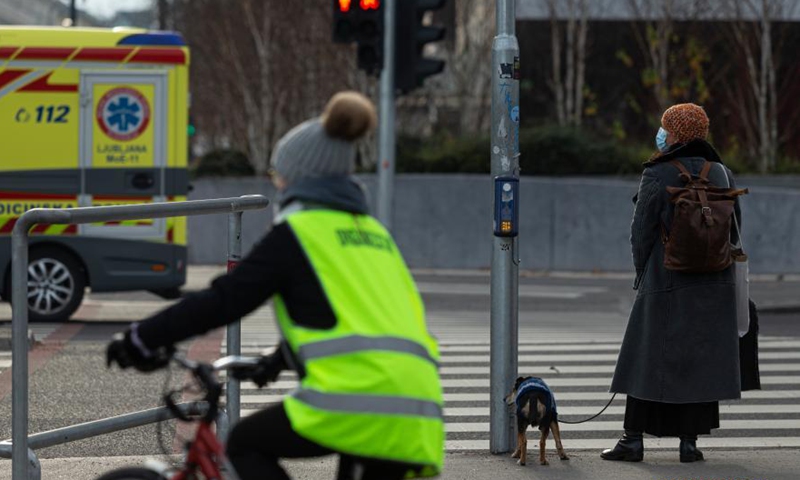 A woman waits for the traffic light in Ljubljana, Slovenia, Dec. 17, 2020. The Slovenian government decided on Thursday to allow more shops to reopen from Dec. 19 to 23 during the holiday season. (Photo by Zeljko Stevanic/Xinhua)
