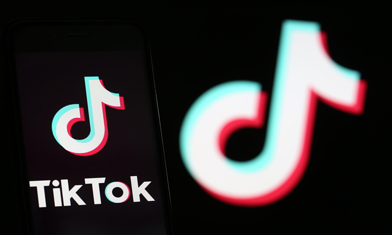 The logo of TikTok is displayed on the screen of a smartphone in front of a TV screen displaying the TikTok logo. Photo: VCG 