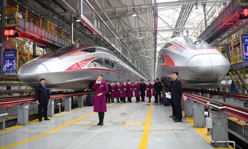 Crew members of the first operation of Fuxing bullet train CR400AF pose for photos in front of the trains at a maintenance station of the railway car depot in west China's Chongqing Municipality, Dec. 23, 2020. Fuxing bullet train CR400AF, assigned to Chongqing Railway for the first time, made debut in Chongqing on Wednesday, expected to start operation Thursday with the service from Shapingba Station in Chongqing to Chengdu East station in Chengdu of west China's Sichuan Province. The trip between the two cities will be shortened from 78 minutes to 62 minutes. (Xinhua/Tang Yi)