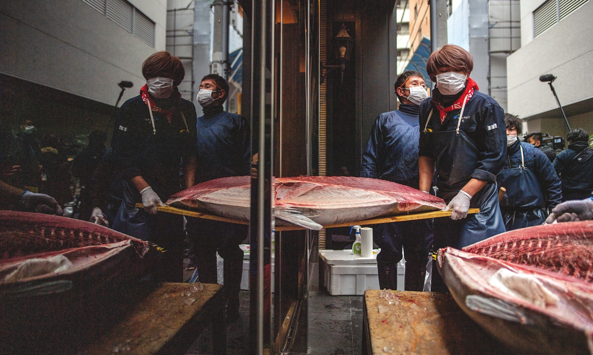 Wholesaler Yukitaka Yamaguchi (back) watches as staff members carry one of the auctioned tuna at a restaurant in Ginza, after the New Year's auction at Toyosu fish market in Tokyo, Japan on Tuesday. Tuna sold at new year auction goes for just 10 percent of 2020 price, according to the Japan Times. Photo: AFP