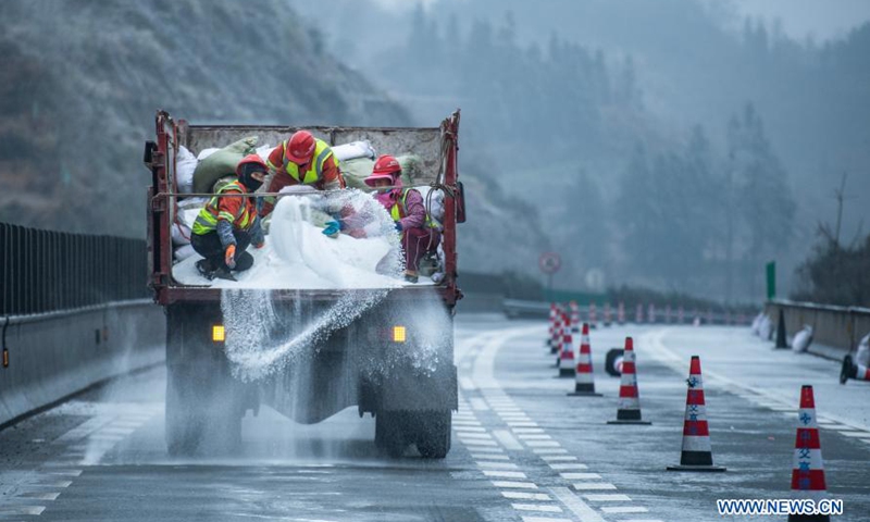Workers sprinkle salt on roads to ensure traffic safety after snow and ...