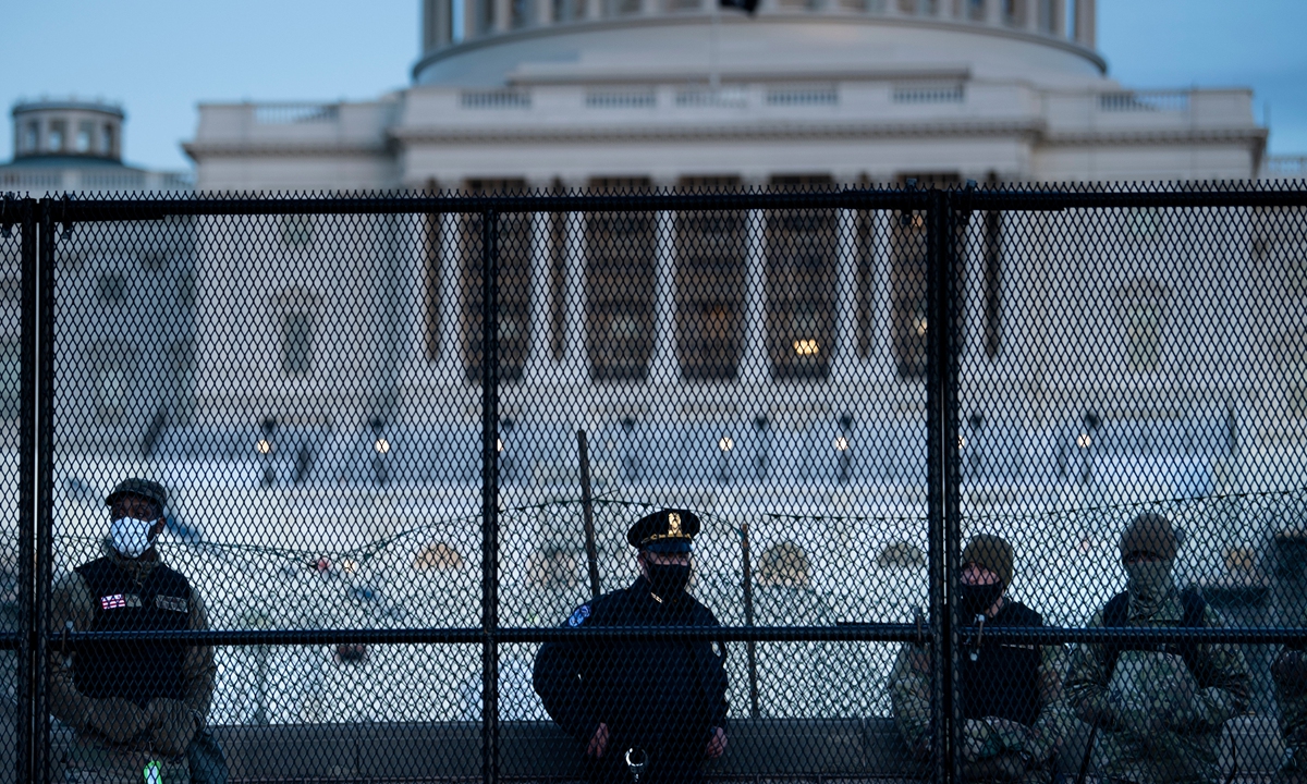 A Capitol police officer stands with members of the National Guard behind a crowd control fence surrounding Capitol Hill a day after a pro-Trump mob broke into the US Capitol on Thursday in Washington, DC. Photo: AFP