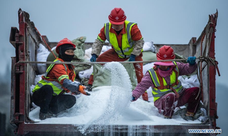 Workers sprinkle salt on roads to ensure traffic safety after snow and ...