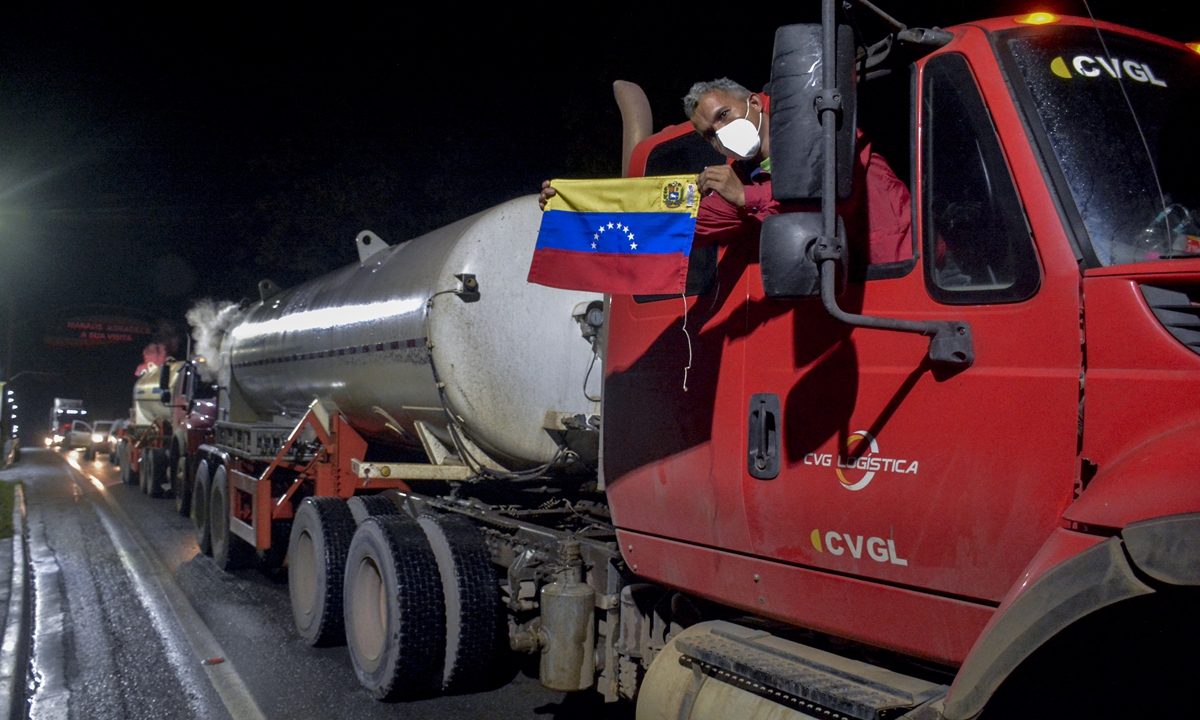 A Venezuelan truck driver holds a national flag as he and others arrive in Brazil bringing oxygen to assist COVID-19 patients in Manaus, Amazonas state, Brazil, on Tuesday. Under an overwhelming heat, dozens of people have been waiting for 12 hours to fill oxygen tanks and try to save the lives of their loved ones in Manaus, a Brazilian city plunged into chaos by the explosion of COVID-19 cases. Photo: AFP