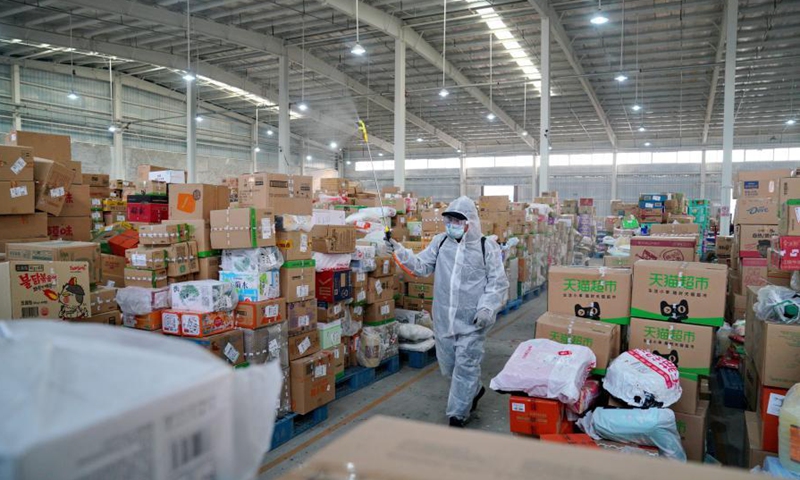 A staff of Shijiazhuang distribution center of Cainiao Network, the logistics platform of e-commerce giant Alibaba, disinfects packages in Shijiazhuang, north China's Hebei Province, Jan. 23, 2021. Logistics companies in Shijiazhuang have strengthened disinfection measures as the COVID-19 prevention and control efforts to make sure the safety of their employees and customers. (Xinhua/Mu Yu)