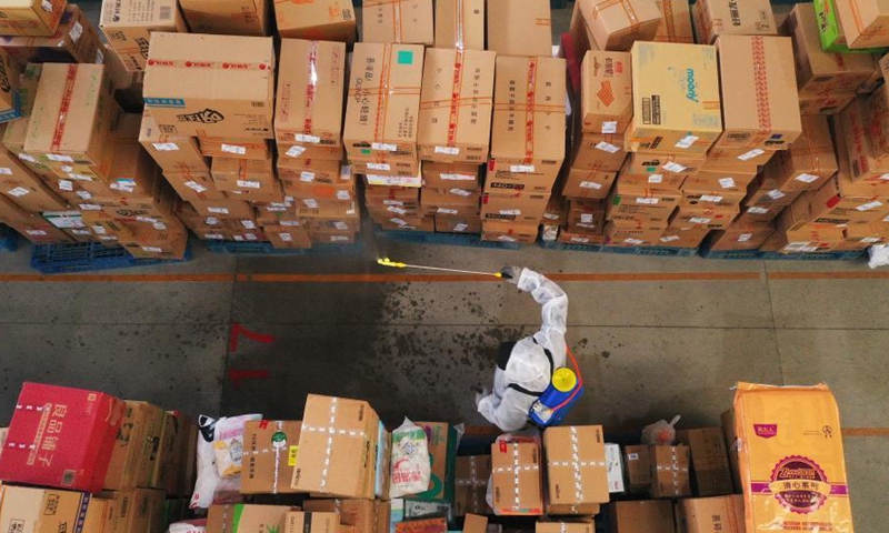 Aerial photo taken on Jan. 23, 2021 shows a staff of Shijiazhuang distribution center of Cainiao Network, the logistics platform of e-commerce giant Alibaba, disinfecting packages in Shijiazhuang, north China's Hebei Province. Logistics companies in Shijiazhuang have strengthened disinfection measures as the COVID-19 prevention and control efforts to make sure the safety of their employees and customers. (Xinhua/Mu Yu) 