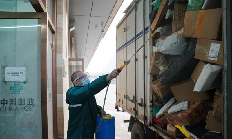 A staff of China Post disinfects packages in Shijiazhuang, north China's Hebei Province, Jan. 23, 2021. Logistics companies in Shijiazhuang have strengthened disinfection measures as the COVID-19 prevention and control efforts to make sure the safety of their employees and customers. (Xinhua/Mu Yu) 
