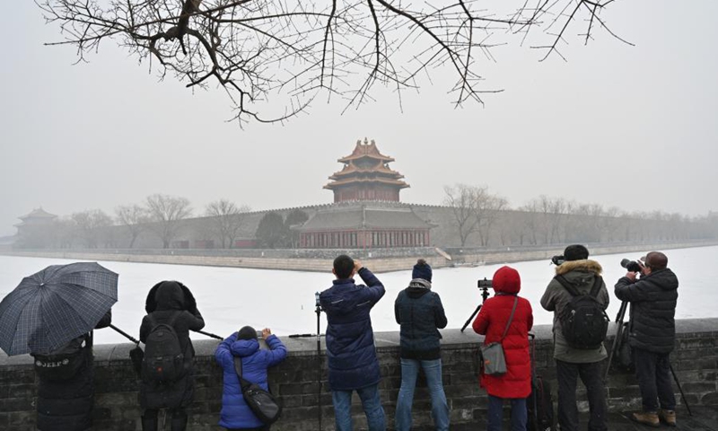 People gather to photograph a turret of the Palace Museum amid falling snow in Beijing, capital of China, Jan. 25, 2021. (Xinhua/Li Xin) 