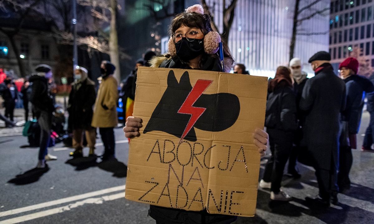 A demonstrator holds a banner reading 