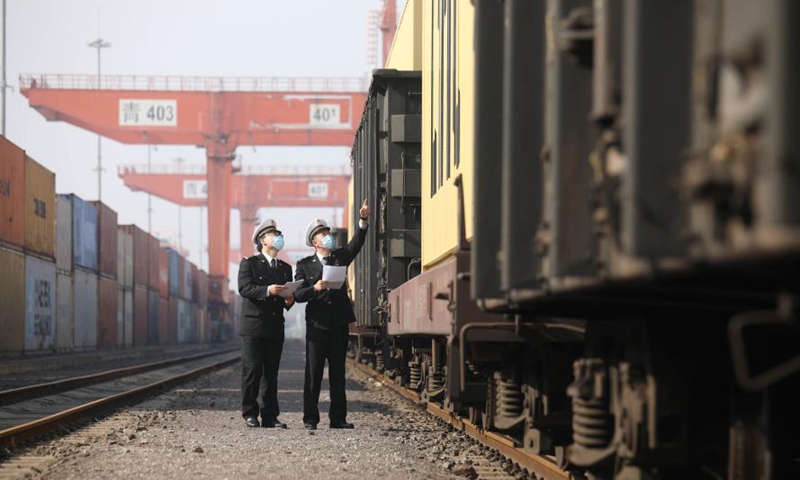 Customs staff members check the first Qilu freight train running from Jiaozhou, east China's Shandong province to Baku, capital of Azerbaijan in Jiaozhou, Jan. 31, 2021. A freight train carrying 100 twenty-foot equivalent unit (TEU) containers' goods such as tires and air conditions left Jiaozhou on Sunday, marking the launch of Qilu freight train services from Jiaozhou to Baku. (Photo by Xie Hao/Xinhua)
