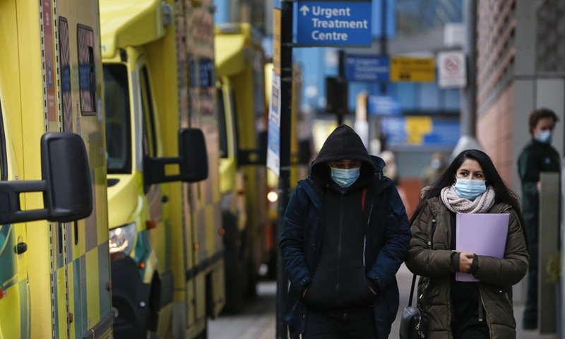 People wearing face masks walk past ambulances at The Royal London Hospital in London, Britain, on Jan. 26, 2021.Photo: Xinhua