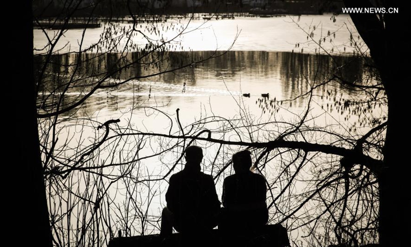 Two visitors enjoy sunshine by the Lake Tegel in Berlin, capital of Germany, Feb. 25, 2021. (Xinhua/Shan Yuqi) 
