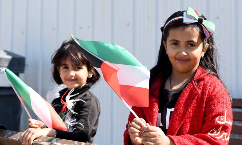 Girls holding Kuwaiti flags play at a square in Kuwait City, Kuwait, Feb. 25, 2021. (Xinhua/Ghazy Qaffaf) 