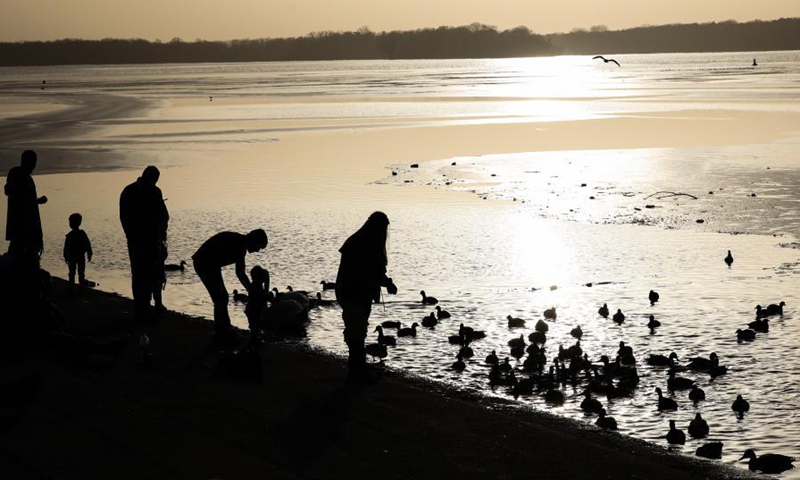 People watch birds by the Lake Tegel covered with thin ice in Berlin, capital of Germany, Feb. 25, 2021. (Xinhua/Shan Yuqi) 
