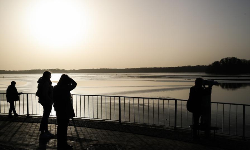 People enjoy sunshine by the Lake Tegel in Berlin, capital of Germany, Feb. 25, 2021. (Xinhua/Shan Yuqi) 