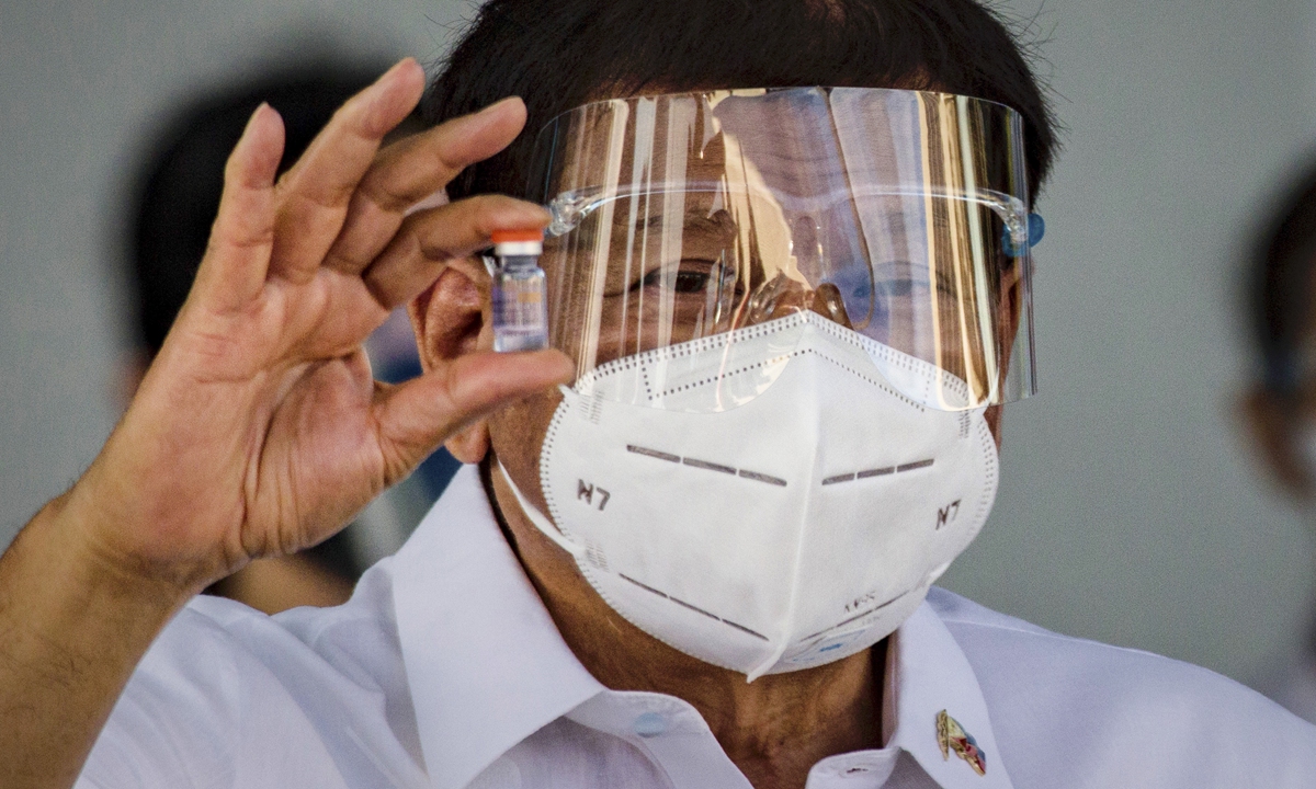 Philippine President Rodrigo Duterte holds up a vial of Sinovac Biotech's COVID-19 vaccine as he witnesses the arrival of a shipment of the vaccines, which were delivered by a Chinese military aircraft, at Ninoy Aquino International Airport on Sunday in Manila, Philippines. Photo: AFP
