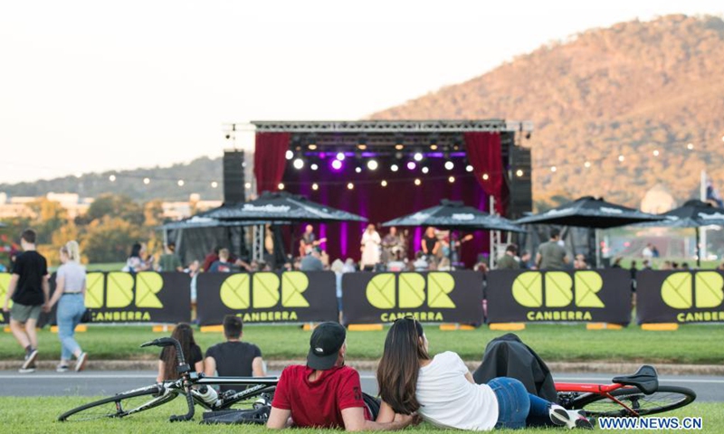 People enjoy music on the lawn during the Enlighten Festival in Canberra, Australia, Feb. 28, 2021. The annual Enlighten Festival runs from Feb. 26 to March 8 in Canberra with landmark buildings illuminated with colorful lights. People visiting the festival this year are required to register in advance and keep social distancing.(Photo: Xinhua)