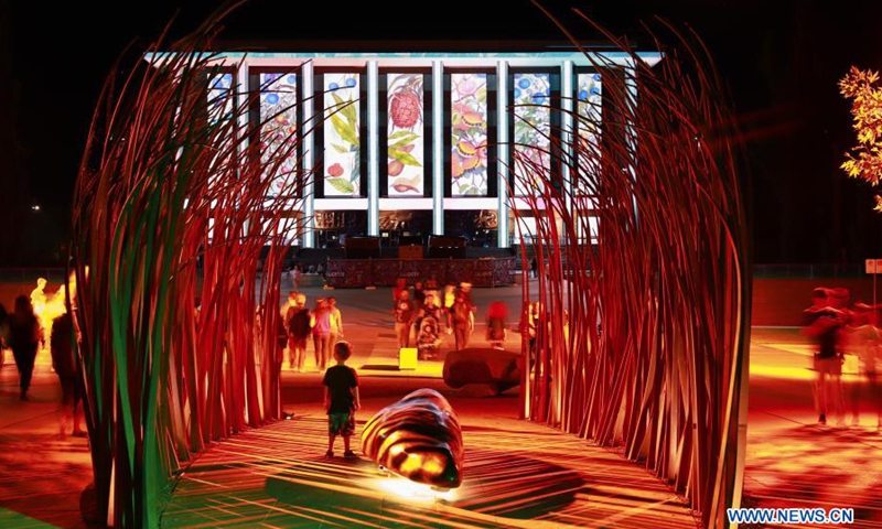 A little boy looks at the light projection on the National Library of Australia during the Enlighten Festival in Canberra, Australia, Feb. 28, 2021. The annual Enlighten Festival runs from Feb. 26 to March 8 in Canberra with landmark buildings illuminated with colorful lights. People visiting the festival this year are required to register in advance and keep social distancing.(Photo: Xinhua)