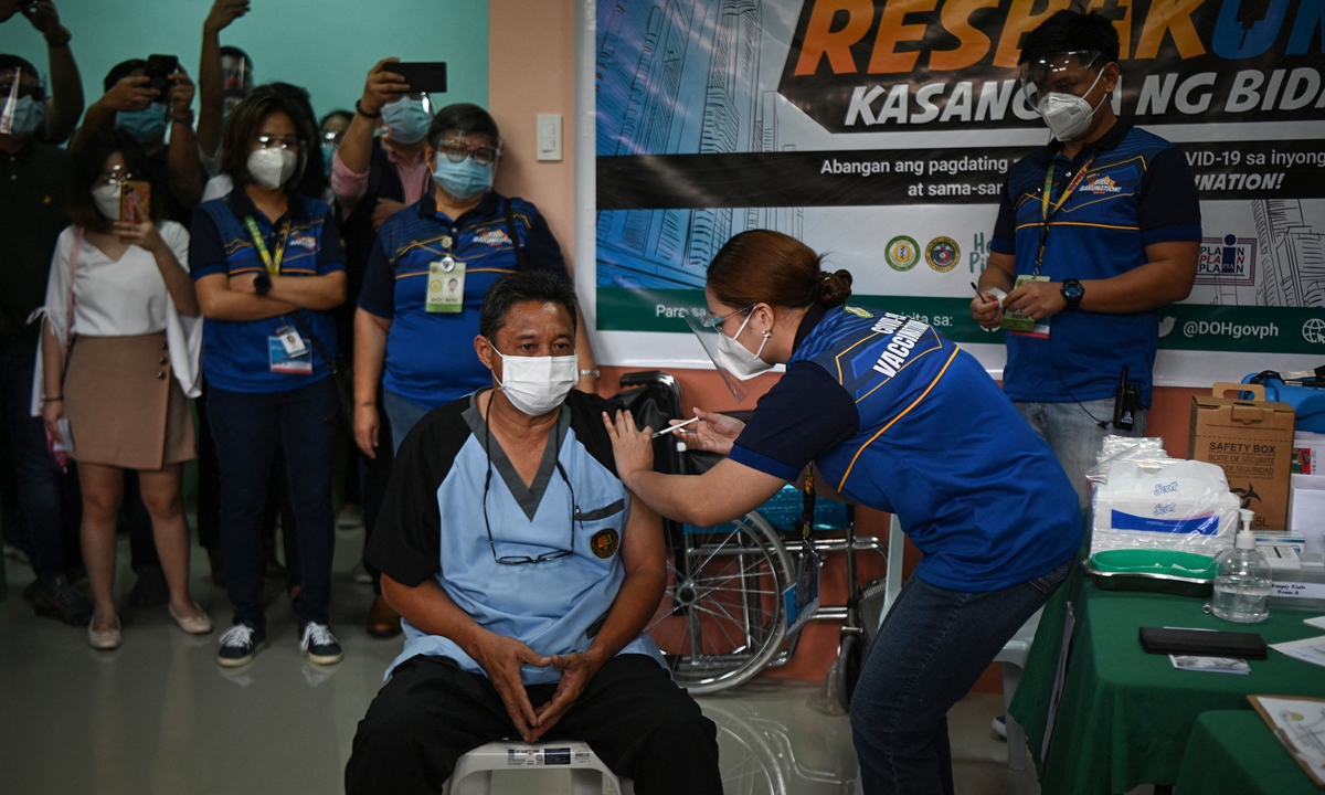 Alfonso Famaran (front left), director of the Dr Jose Rodrigues memorial hospital, receives the Sinovac COVID-19 vaccine during the first phase of vaccinations for health workers in Manila, the Philippines on Monday. Photo: AFP