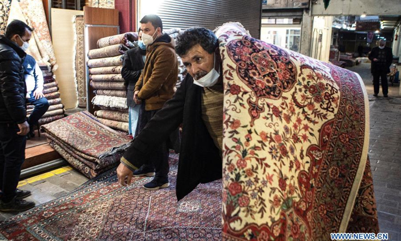 A man carries a hand-woven carpet at an old carpet bazaar in downtown Tehran, Iran, Feb. 27, 2021.(Photo: Xinhua)