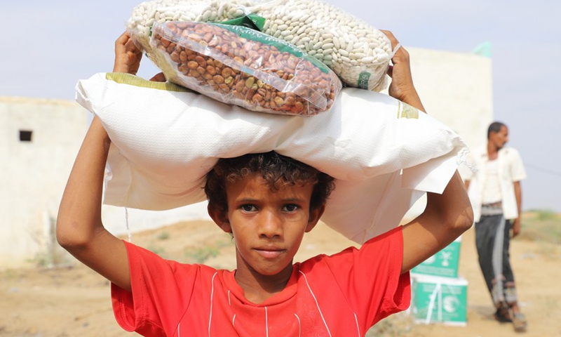 Photo taken on Feb. 14, 2021 shows a boy carrying the food donated by a charity group in Hajjah Province, north Yemen. (Photo: Xinhua)
