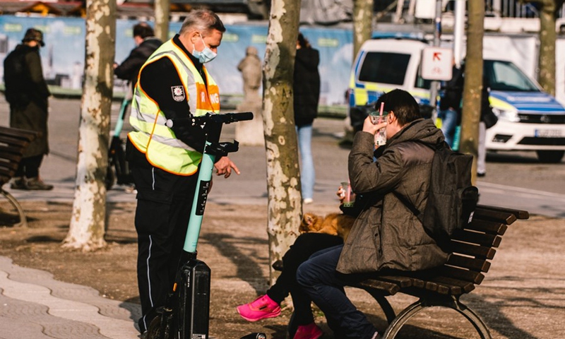 A policeman asks people to wear face masks and not to stay in public area near Rhine river amid the COVID-19 pandemic in Dusseldorf, Germany, Feb. 27, 2021.(Photo: Xinhua)