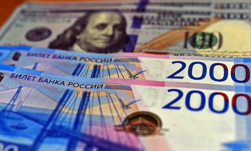 Des billets en roubles russes sont vus avec des dollars américains en arrière-plan le 2 mars 2021. (Photo : Xinhua)