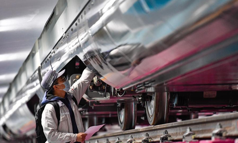 A technician checks a train of the Guangzhou Metro Line 18 in Guangzhou, south China's Guangdong Province, March 3, 2021. The electric train, with a maximum designed speed of 160 km per hour, carried out the first hot-running test in the small hours of Thursday morning, in order to conduct a comprehensive inspection of the subway power supply, signal, communication, line, and electromechanical system of the line.Photo:Xinhua