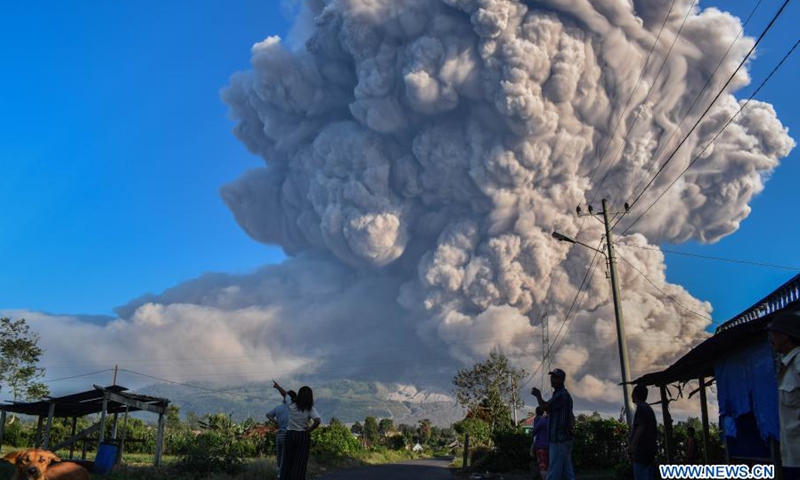 People watch volcanic materials being spewed from Mount Sinabung in Karo, North Sumatra, Indonesia, on March 2, 2021. Mount Sinabung on the Indonesian island of Sumatra erupted on Tuesday, spewing ash clouds as high as 5,000 meters into the sky. There were no reports of casualties or damages.(Photo: Xinhua)