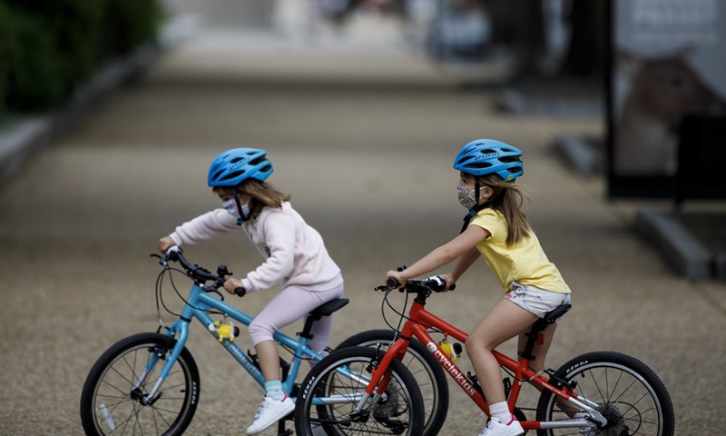 Children wearing masks ride bicycles on the National Mall in Washington D.C., the United States, May 18, 2020.(Photo: Xinhua)