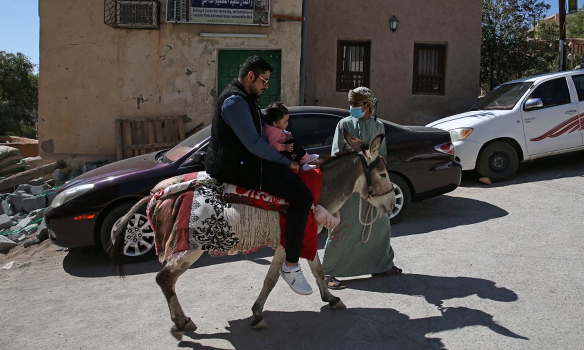 Tourists ride a donkey in the village of Misfat al-Abriyeen on February 8. Photo: AFP

