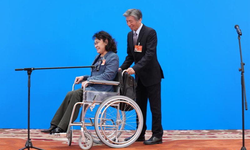 Fan Di'an (R), a member of the 13th National Committee of the Chinese People's Political Consultative Conference (CPPCC), pushes Zhang Haidi, also a member of the 13th CPPCC National Committee, in her wheelchair to help her leave after receiving interview via video link ahead of the opening of the fourth session of the 13th CPPCC National Committee at the Great Hall of the People in Beijing, capital of China, March 4, 2021. (Xinhua/Li He)