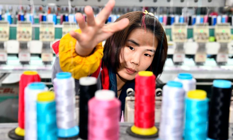 A worker adjusts threads at a manufacturing shop in Ligezhuang Town in Jiaozhou, east China's Shandong Province, March 4, 2021. Over the past 30 years, Ligezhuang Town, a major manufacturing base and collecting and distributing center featuring hat-related products, has achieved industrial upgrading, providing one-stop service for buyers worldwide.Photo:Xinhua