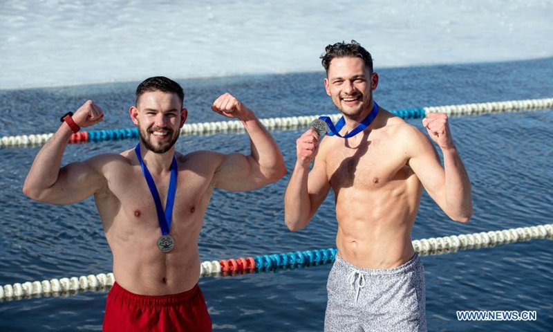 Two swimmers pose with the medals after a winter swimming race on the Green Lake in Vilnius, Lithuania, on March 6, 2021. A 25-meter winter swimming race was held here on Saturday.Photo:Xinhua