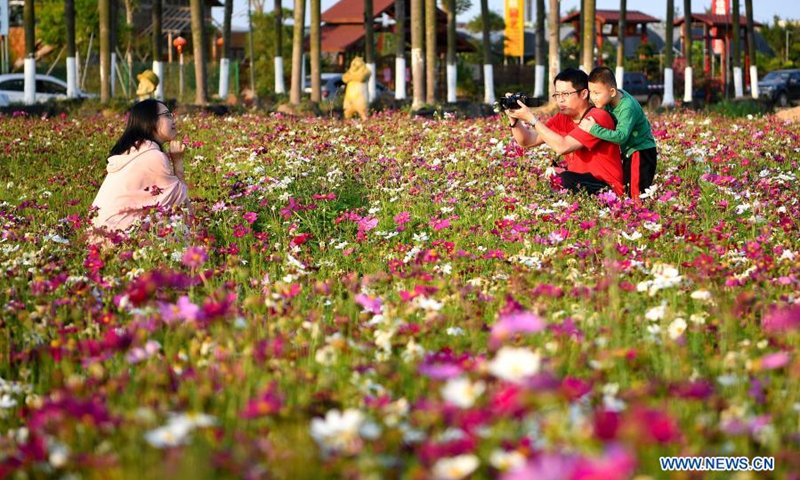 People take photos amid blooming flowers in Haikou, south China's Hainan Province, March 6, 2021.(Photo: Xinhua)