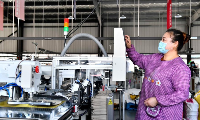 A worker monitors a hat manufacturing equipment in Ligezhuang Town in Jiaozhou, east China's Shandong Province, March 4, 2021. Over the past 30 years, Ligezhuang Town, a major manufacturing base and collecting and distributing center featuring hat-related products, has achieved industrial upgrading, providing one-stop service for buyers worldwide.Photo:Xinhua