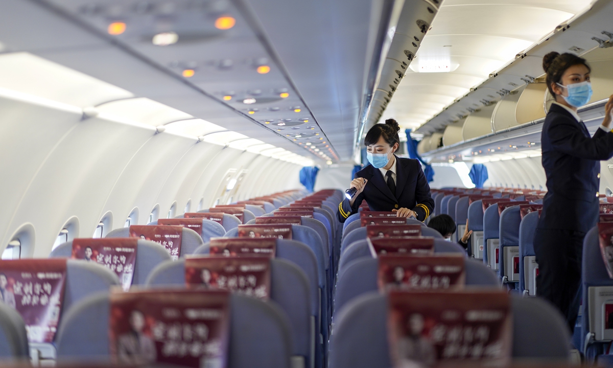 Members of the female in-flight security team, checks the luggage-rack on a flight.