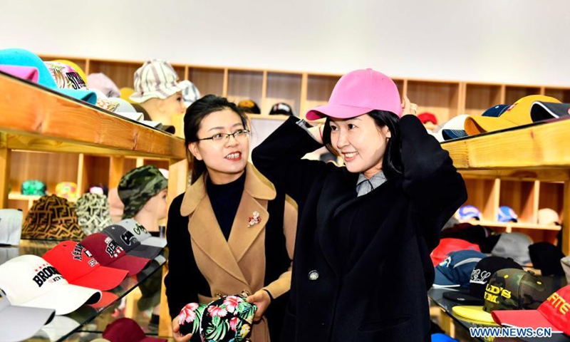 Citizens try hats at a showroom in Ligezhuang Town in Jiaozhou, east China's Shandong Province, March 4, 2021. Over the past 30 years, Ligezhuang Town, a major manufacturing base and collecting and distributing center featuring hat-related products, has achieved industrial upgrading, providing one-stop service for buyers worldwide.Photo:Xinhua