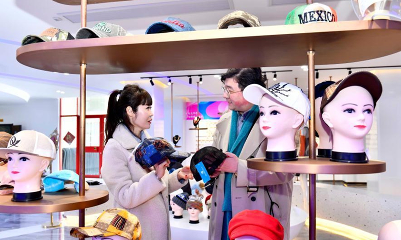 Chinese designer Jiang Shixiang (R) communicates with a South Korean designer on hat design at an industrial park in Qingdao, east China's Shandong Province, March 4, 2021. Over the past 30 years, Ligezhuang Town, a major manufacturing base and collecting and distributing center featuring hat-related products, has achieved industrial upgrading, providing one-stop service for buyers worldwide.Photo:Xinhua