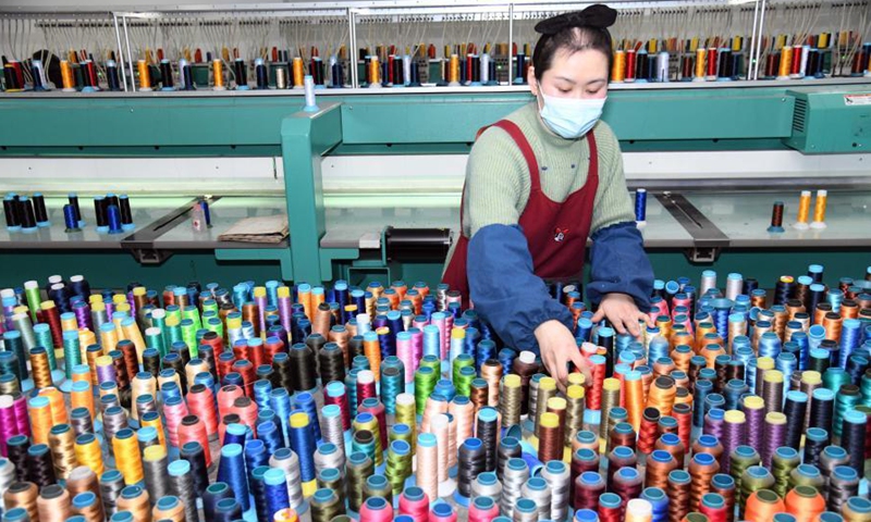 A worker adjusts threads at a hat manufacturing shop in Ligezhuang Town in Jiaozhou, east China's Shandong Province, March 4, 2021. Over the past 30 years, Ligezhuang Town, a major manufacturing base and collecting and distributing center featuring hat-related products, has achieved industrial upgrading, providing one-stop service for buyers worldwide.Photo:Xinhua