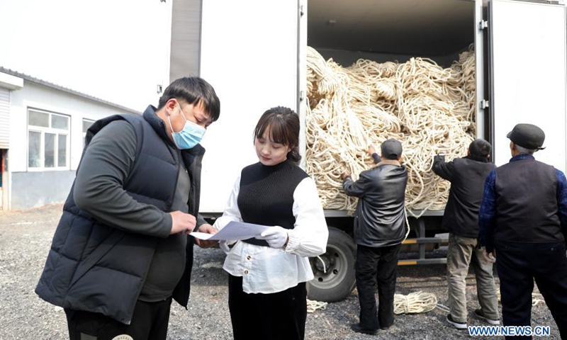 Yan Jiaxin (2nd L) handles invoices with a material delivery worker in Qiaotuo Village of Tai'an County, Anshan, northeast China's Liaoning Province, March 4, 2021.Yan Jiaxin is a household name in her hometown Qiaotuo Village, because the 21-year-old entrepreneur has been running a handicraft factory which employs local women and sells products to European markets.Photo:Xinhua