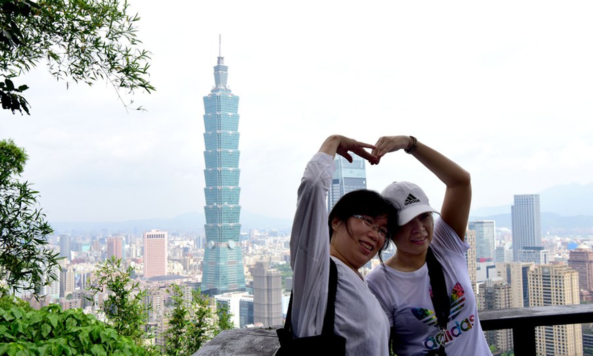 Tourists pose for a photo at Xiangshan Mountain in Taipei, southeast China's Taiwan, July 21, 2019. (Xinhua/Zhu Xiang)