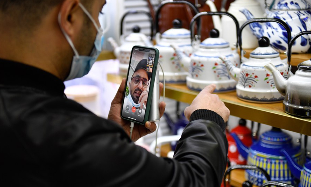 A Yemeni trader selects teapots while communicating with his Saudi Arabian client via video link at the Yiwu International Trade Market in Yiwu city of east China's Zhejiang Province, Jan. 14, 2021. (Xinhua/Huang Zongzhi)