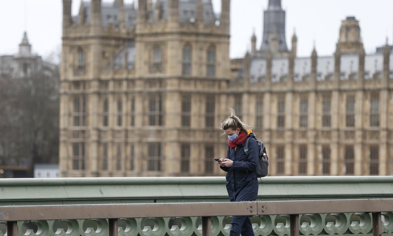 A woman wearing a face mask walks along Westminster Bridge in London, Britain, on Feb. 17, 2021.(Photo: Xinhua)