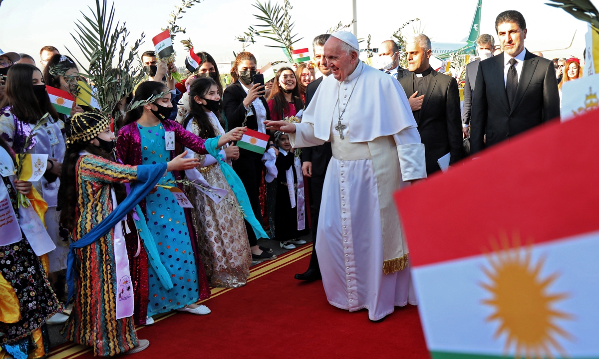 Pope Francis (center), accompanied by the President of the autonomous Kurdistan Region Nechirvan Barzani (right), greets people dressed in traditional outfits upon his arrival at Arbil airport on Sunday, in the capital of the northern Iraqi Kurdish autonomous region. Photo: AFP